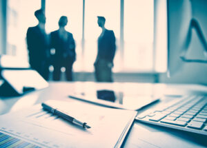 Business devices and documents at the workplace, unrecognized businesspeople sharing the ideas on the background